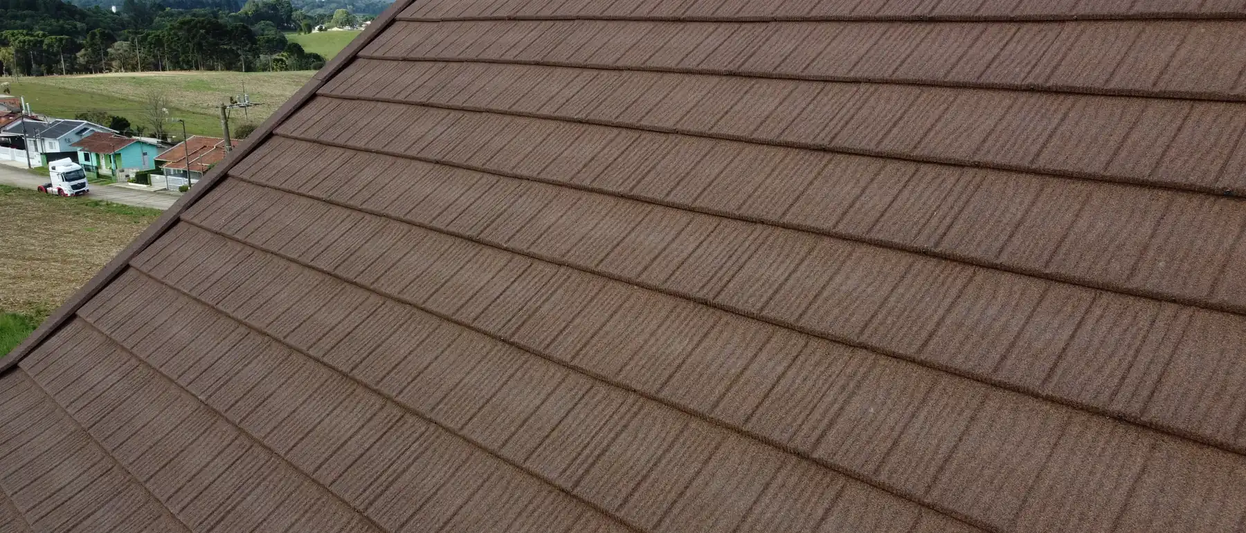 Detalhe da textura de pedra natural e das fileiras de telhas Rock Steel na cor Brownwood.